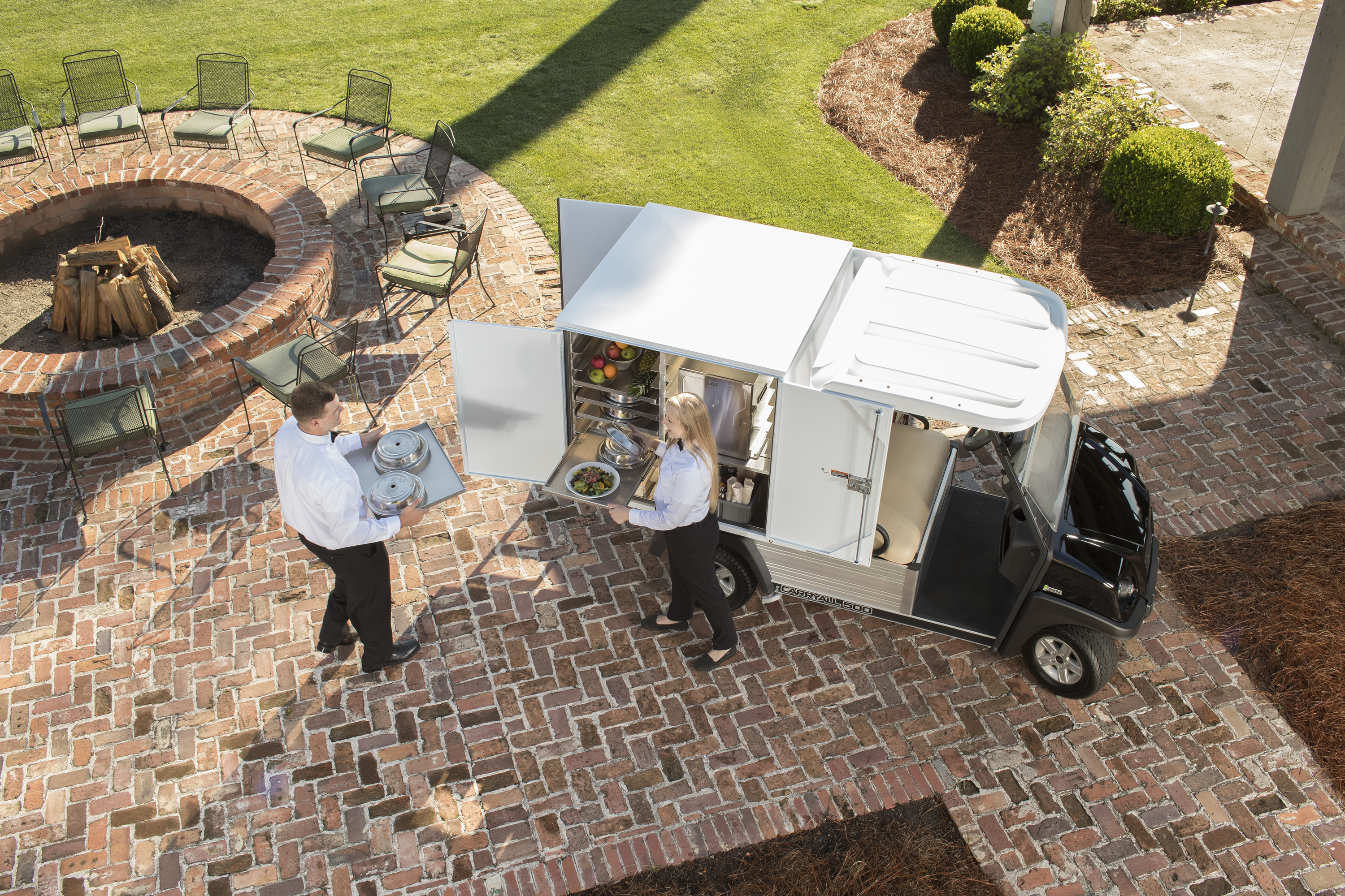 Food services outside on a patio with a custom club car that holds food trays and warmers. 